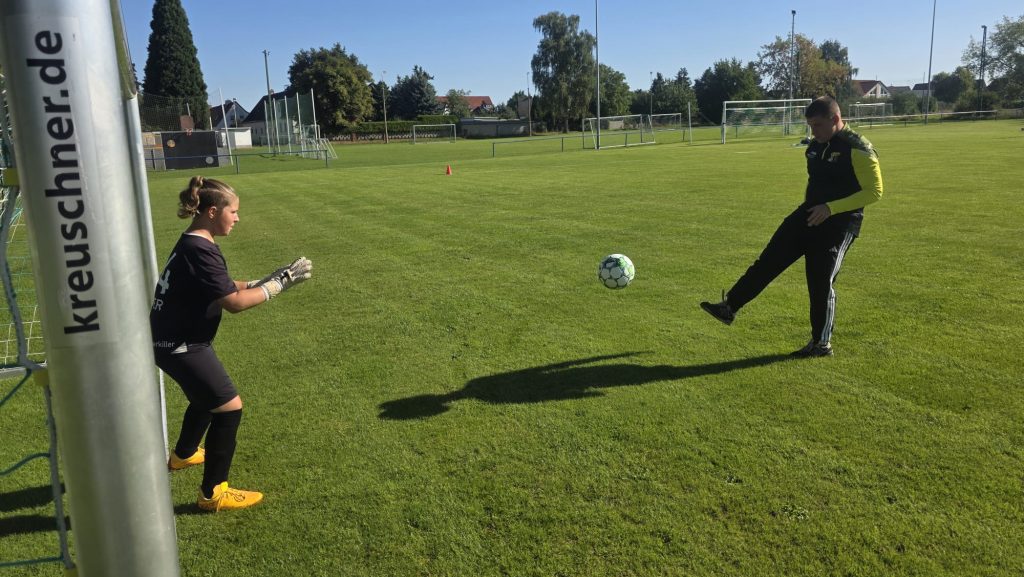 Torwart der D2 beim Aufwärmen mit Trainer auf dem Fußballplatz.