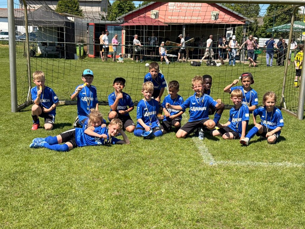Die glücklichen Turniersieger des F-Jugend Frühjahrscups jubeln mit ihren Medaillen auf dem Sportplatz Schenkenberg.