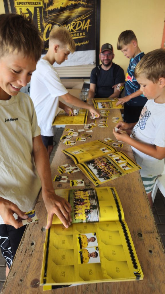 Gruppe Jugendlicher klebt gemeinsam Sticker ein beim Vereinsfest SV Concordia Schenkenberg