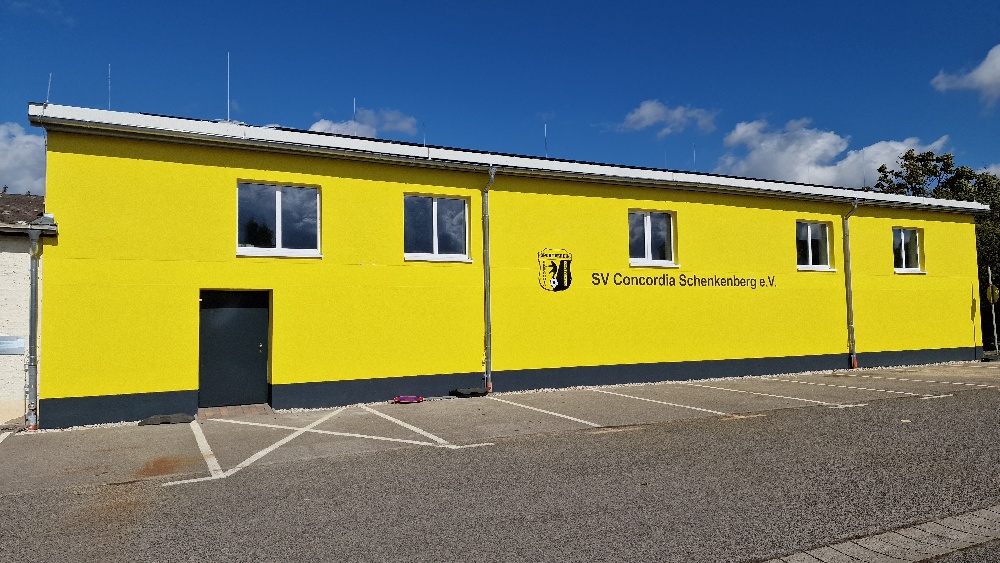Sanierte Turnhalle des SV Concordia Schenkenberg mit gelber Fassade und Vereinslogo